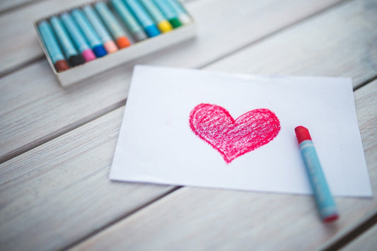 Red heart coloured with crayon on a white sheet of paper